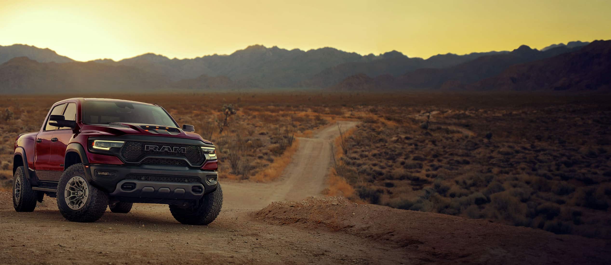 A Ram 1500 TRX truck on a dirt road at dusk.
