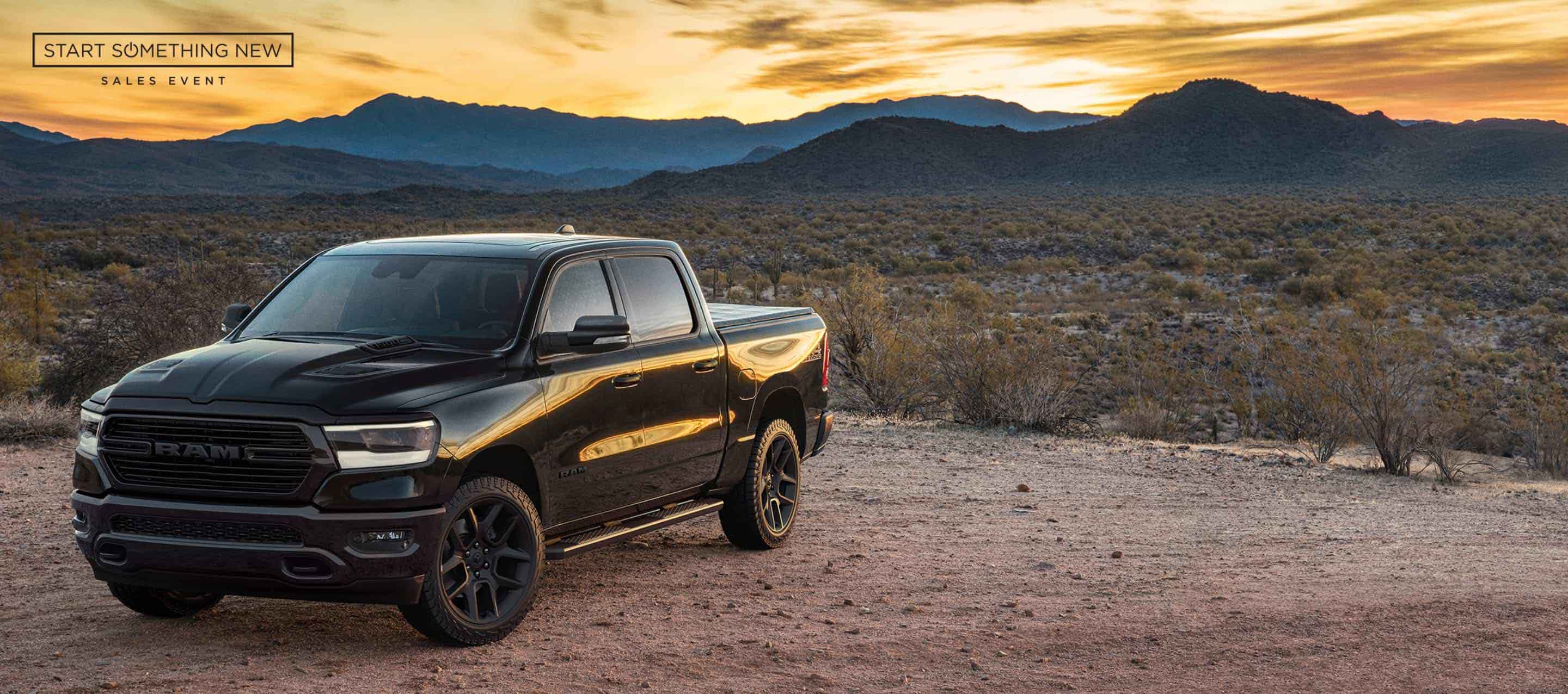 A black 2024 Ram 1500 Laramie Crew Cab in the desert.  The Start Something New Sales Event.