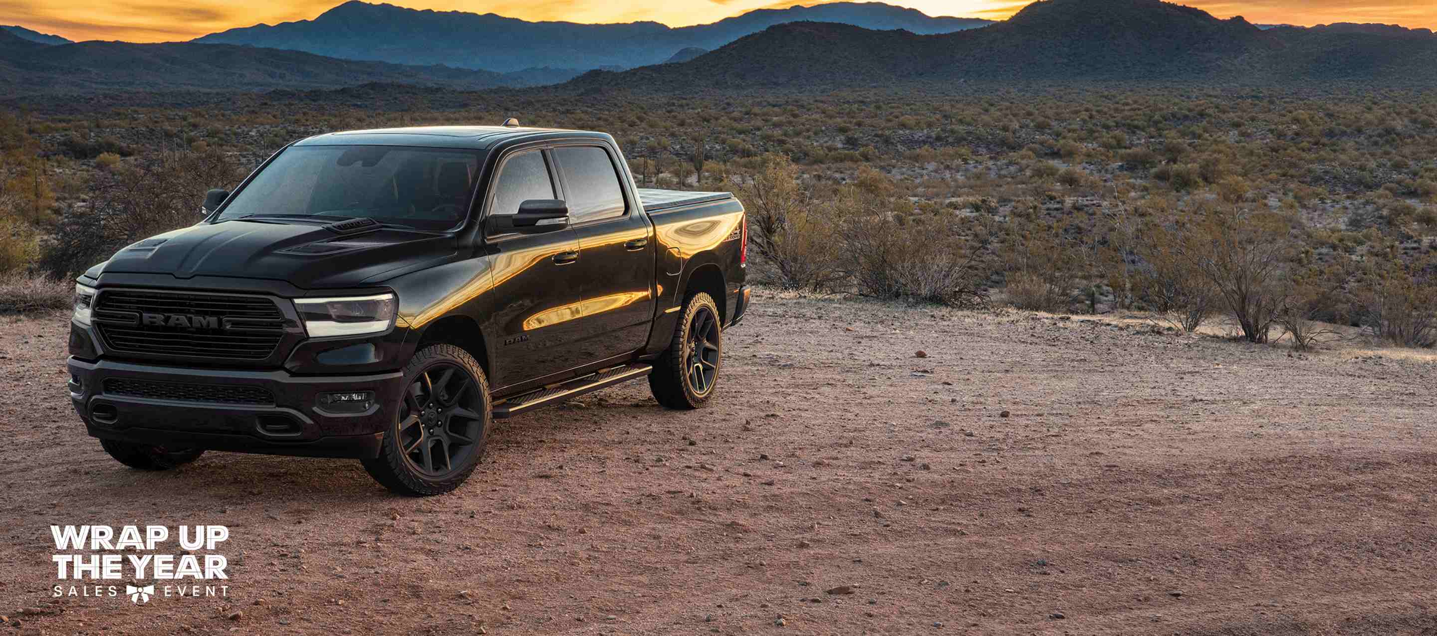 A black 2024 Ram 1500 Laramie Crew Cab in the desert. The Wrap Up The Year Sales Event.