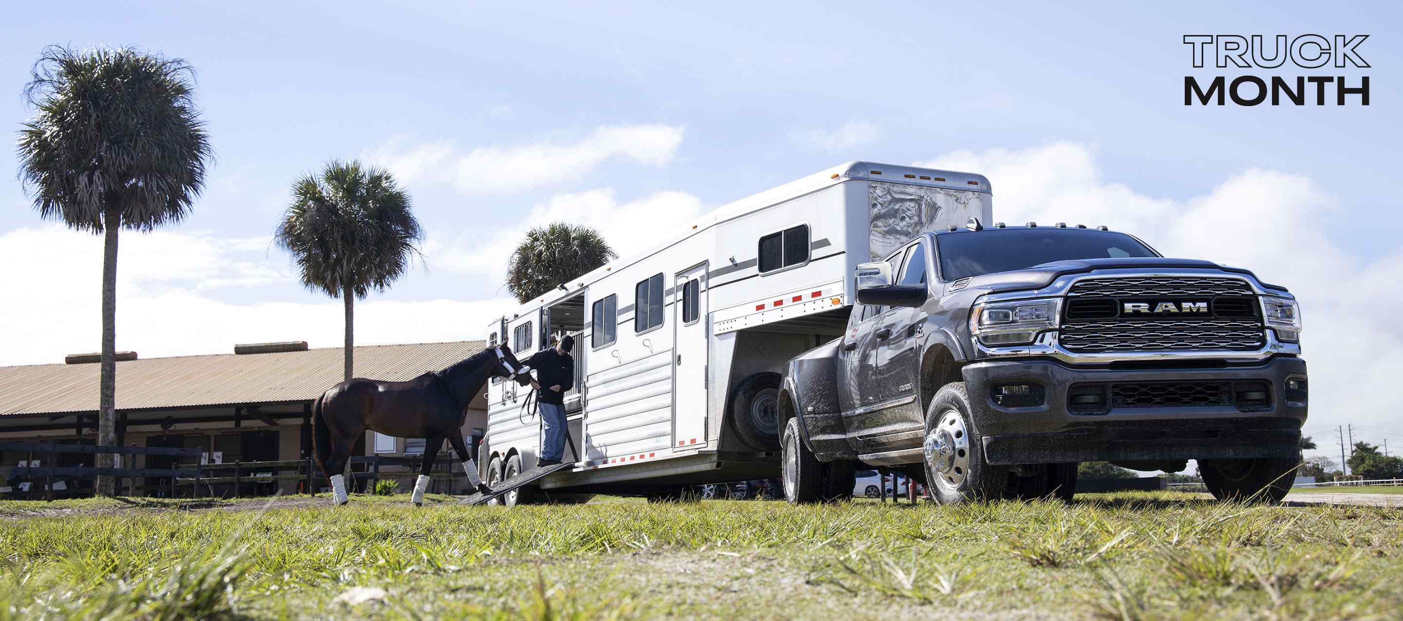 A 2024 Ram 3500 Limited 4x4 Crew Cab towing a fifth wheel horse trailer with a man leading a horse into the trailer. Truck Month Sales Event.