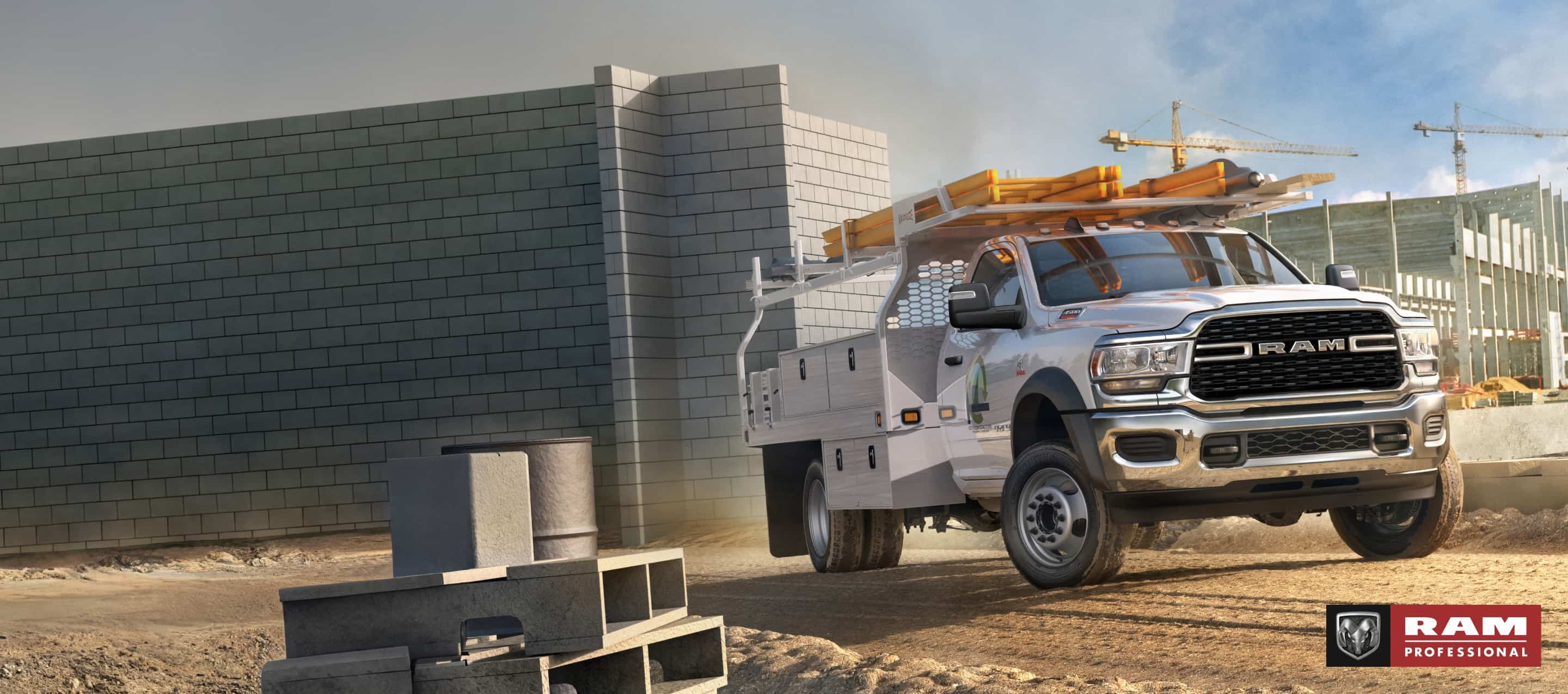 A white 2024 Ram 4500 Chassis Cab Regular Cab with a utility upfit, parked at a large commercial construction site. Ram Professional.