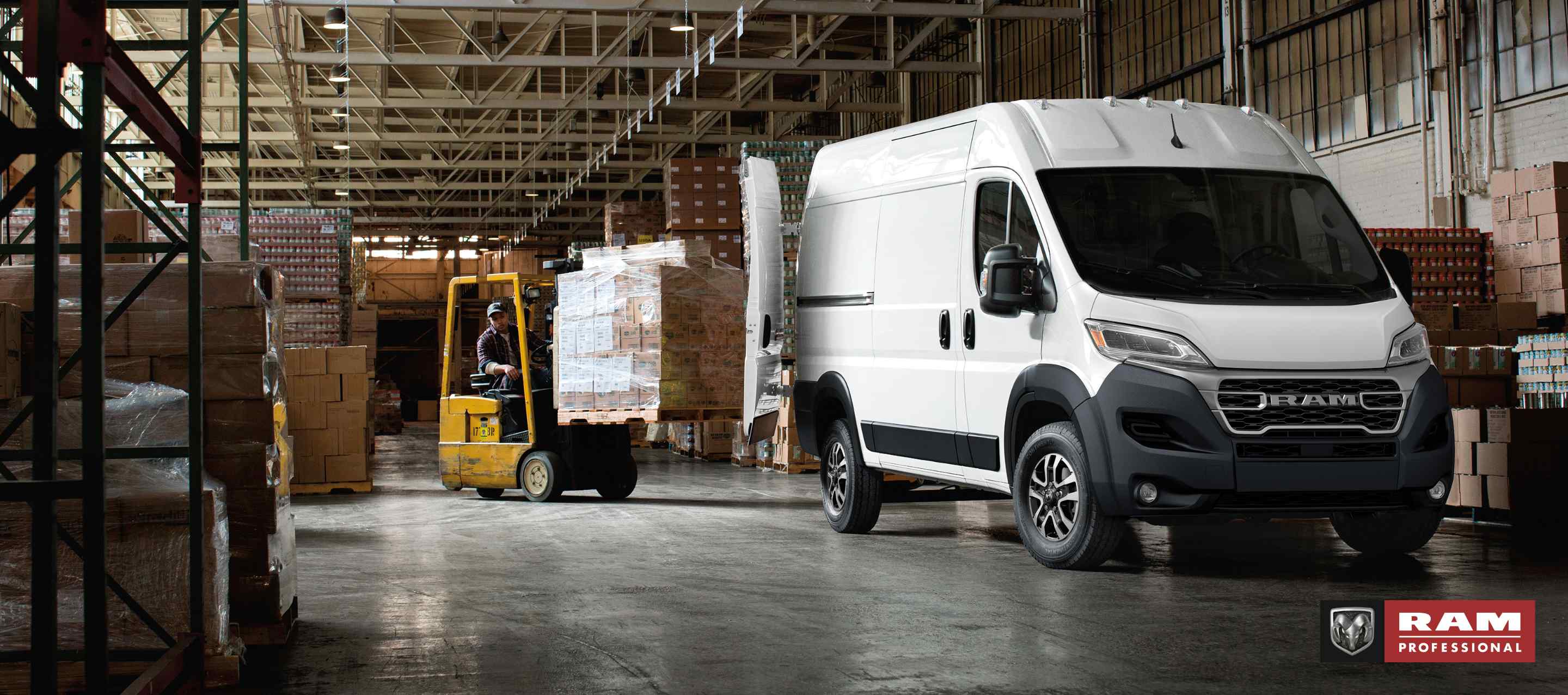 A white 2024 Ram ProMaster 2500 SLT Cargo Van High Roof, with its rear doors fully open and a forklift with a pallet of boxes being driven toward the back of the van. Ram Professional.