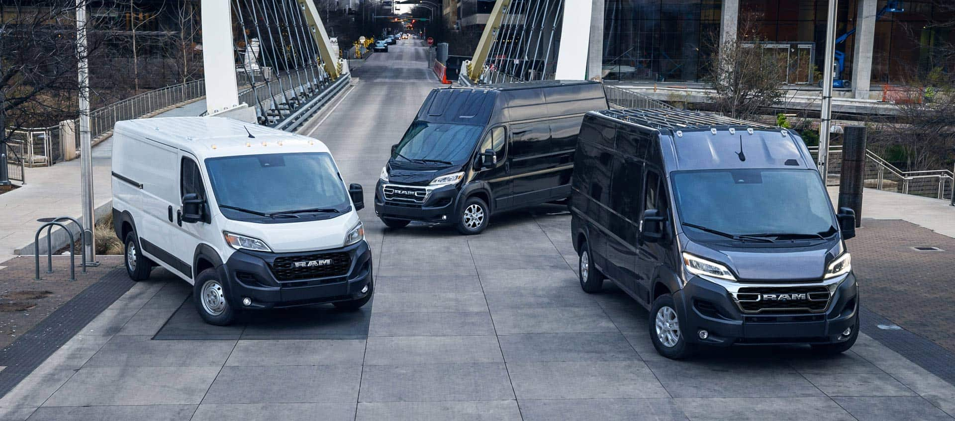 Three 2025 Ram ProMaster Cargo Vans. From left to right: a white Ram ProMaster 1500 Tradesman Standard Roof, a black 3500 SLT Plus Super High Roof and a black 3500 SLT High Roof.