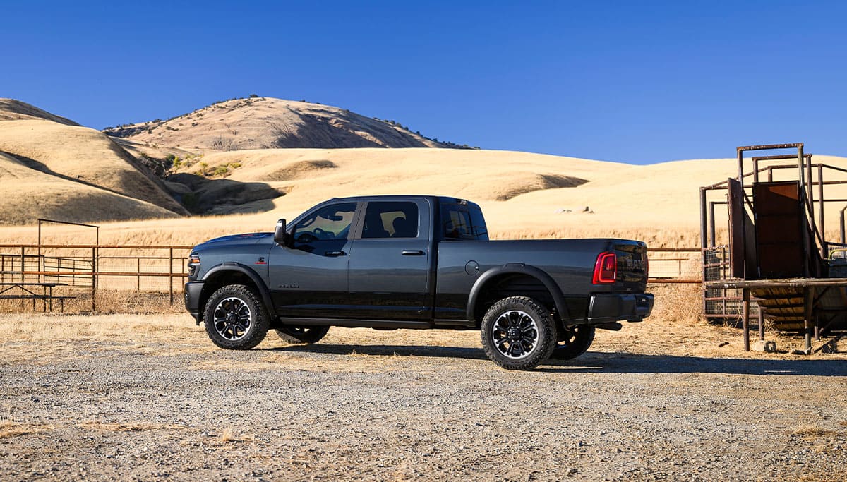 Display A driver-side profile of a gray 2025 Ram 2500 Rebel 4x4 Crew Cab parked at a ranch.