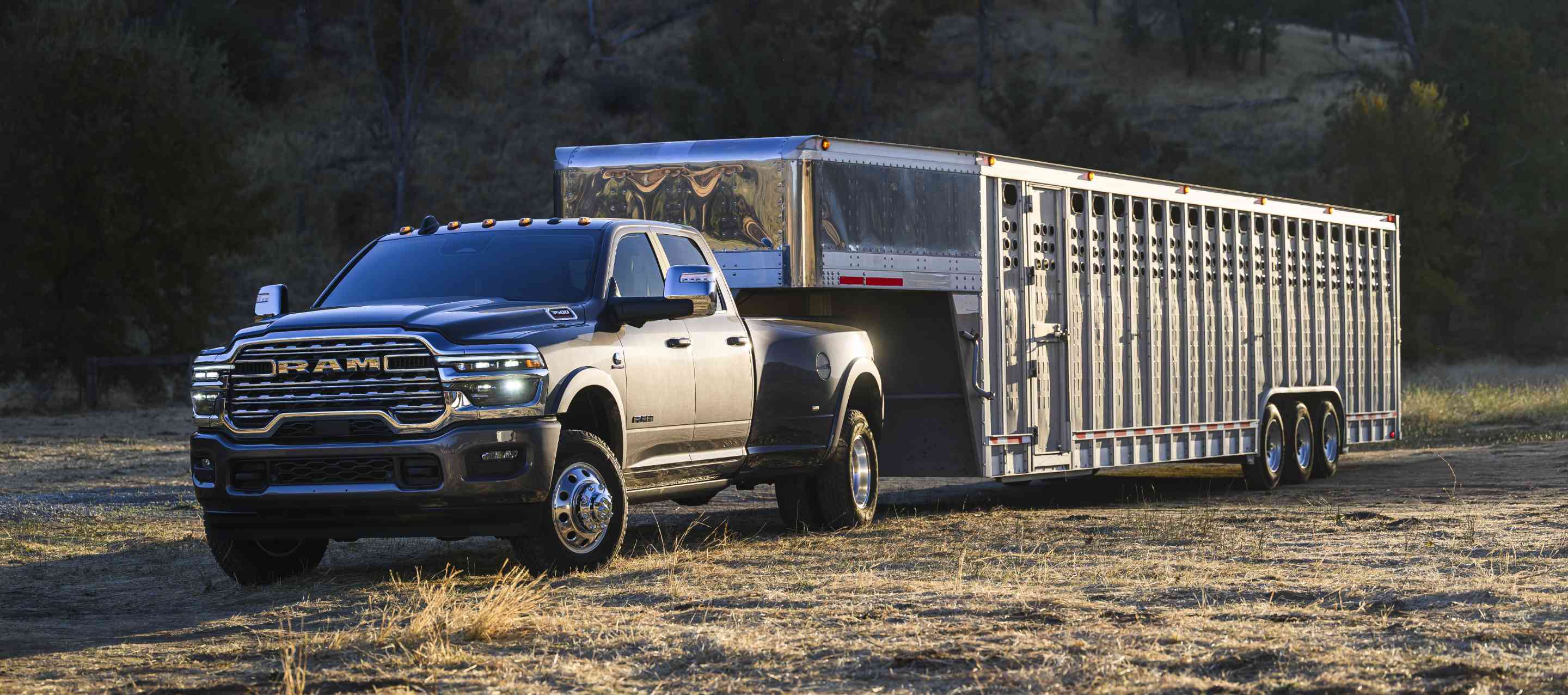 A gray 2025 Ram 3500 Limited Longhorn 4x4 Crew Cab towing a large fifth-wheel livestock trailer.