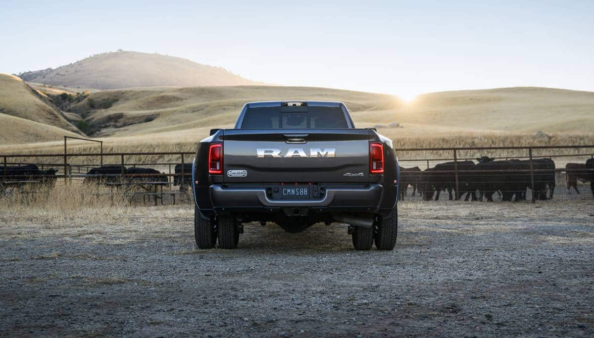 Display The rear angle of a gray 2025 Ram 3500 Limited Longhorn 4x4 Crew Cab parked at a cattle ranch.