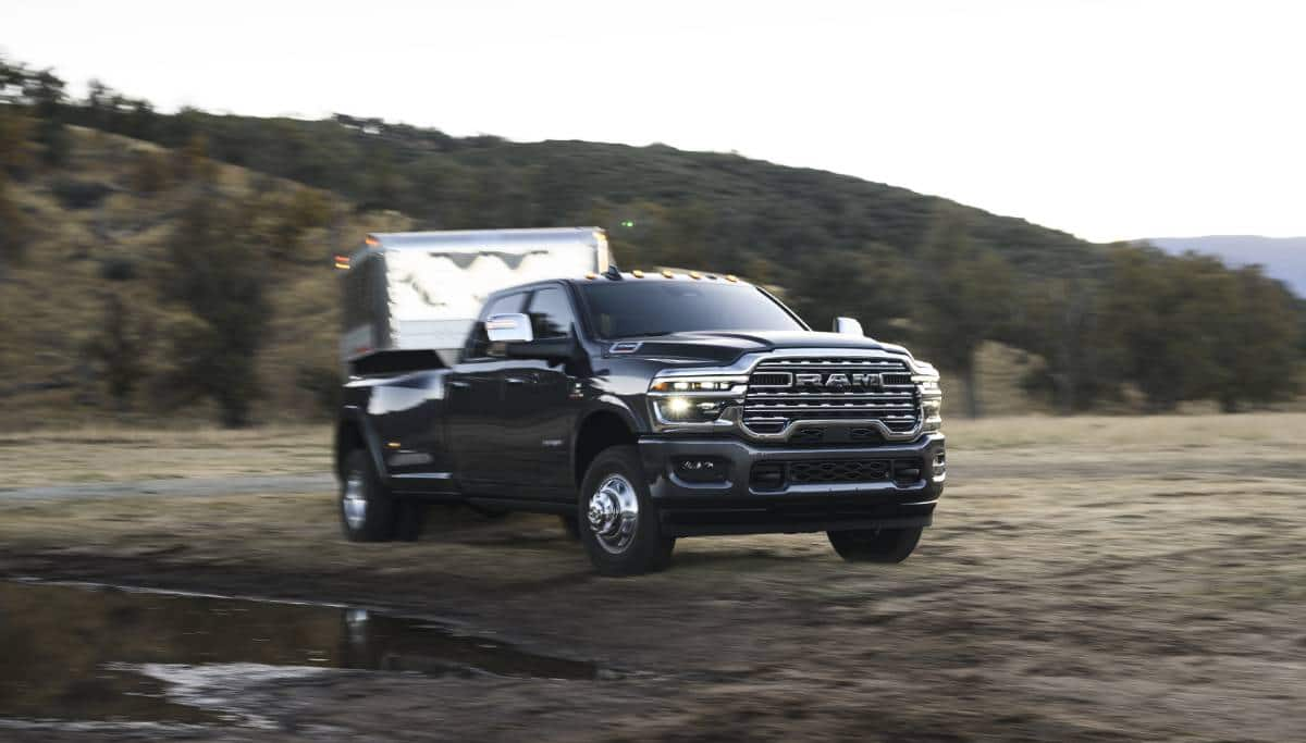 Display A black 2025 Ram 3500 Limited Longhorn 4x4 Crew Cab towing a large fifth-wheel livestock trailer.