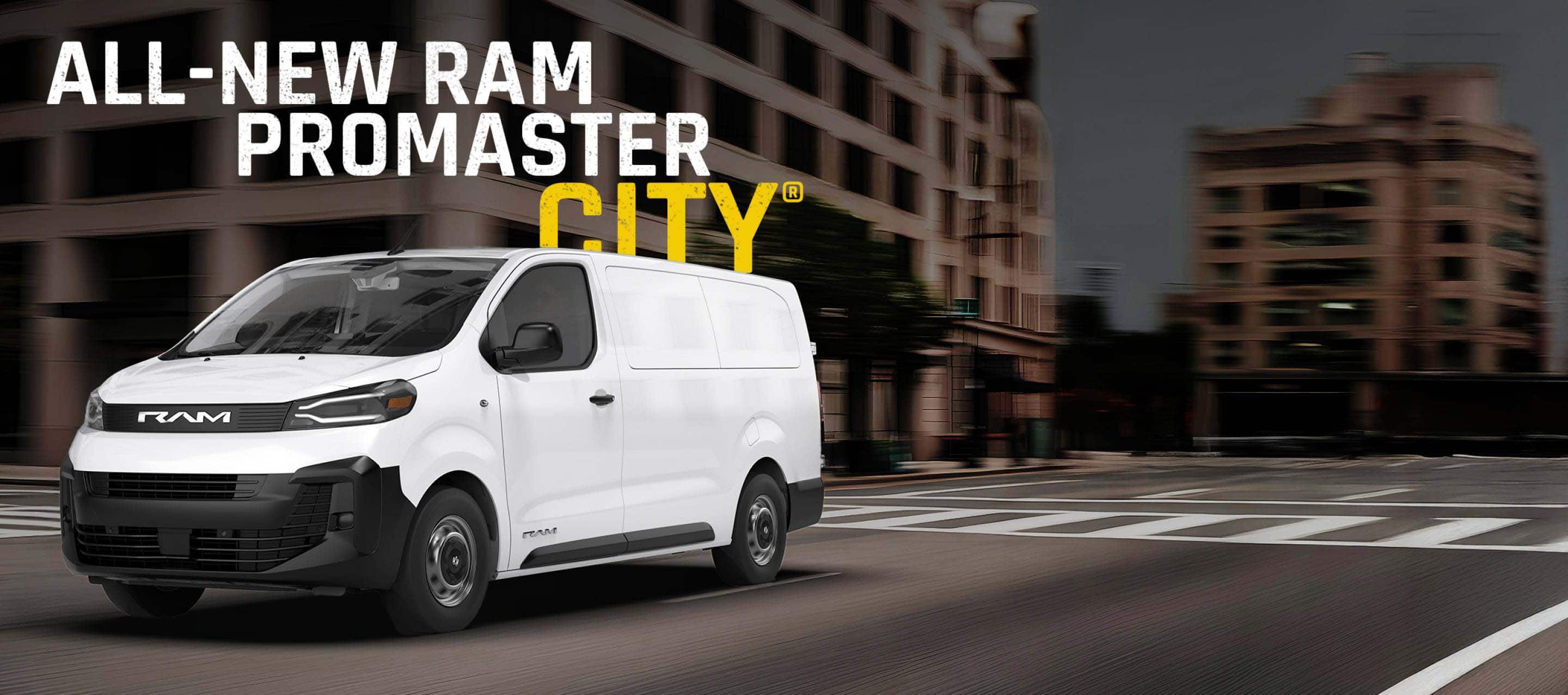 A white 2027 Ram ProMaster City Tradesman Cargo Van traveling through an intersection on a city street. All-New Ram ProMaster City.