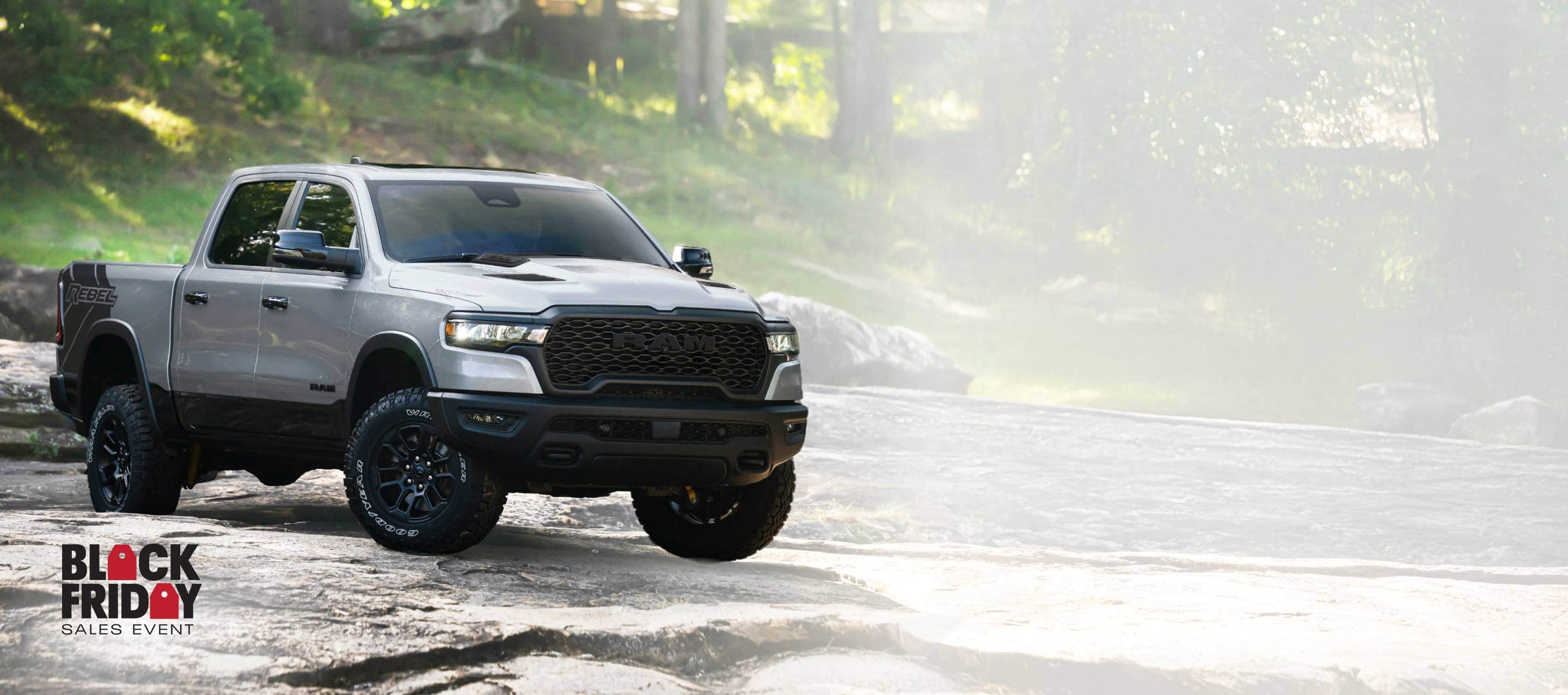A silver 2026 Ram 1500 Rebel 4x4 Crew Cab traveling across an uneven trail off-road. America’s best full-size truck powertrain. Black friday sales event.
