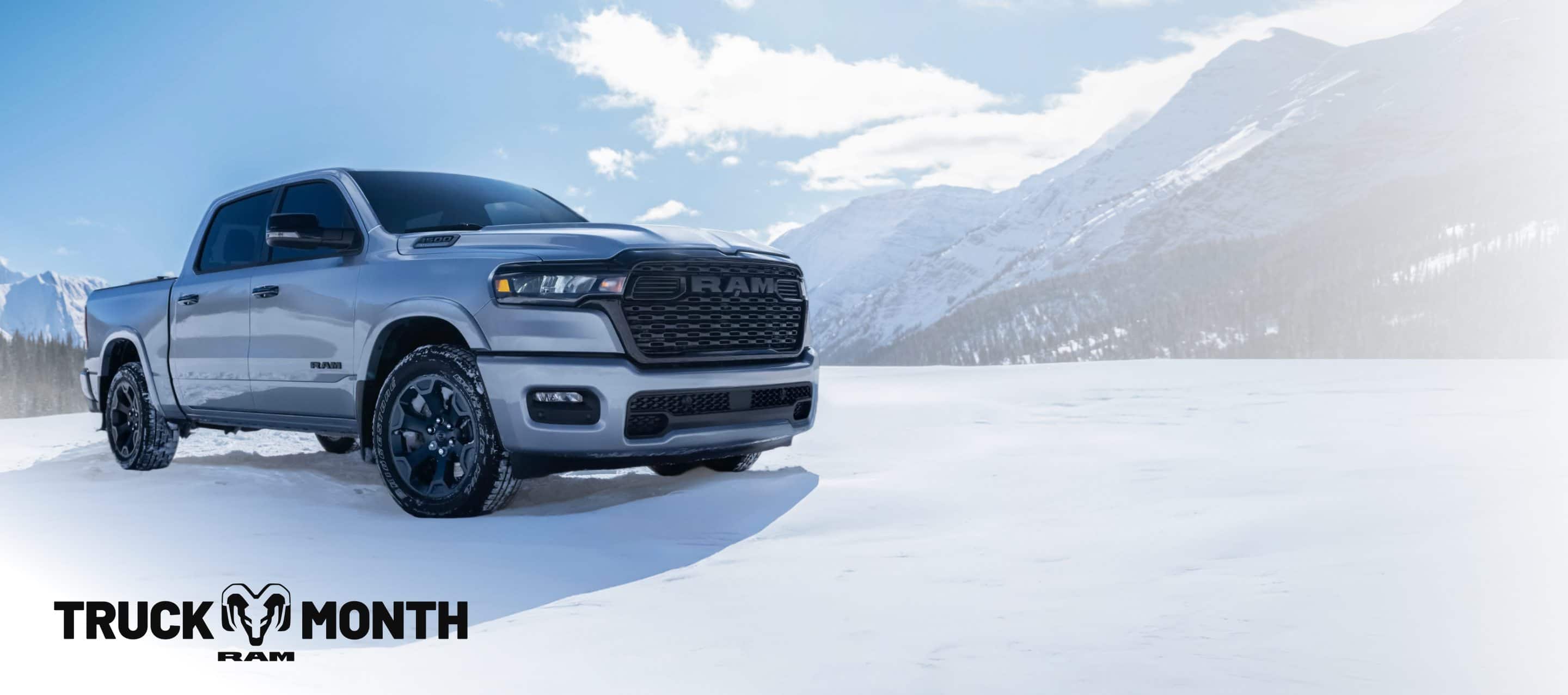 A white 2026 Ram 1500 Big Horn 4x4 Crew Cab parked on a snow-covered clearing off-road in the mountains. Truck of the Month Sales Event.