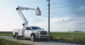 A Ram 5500 Chassis Cab with a crane upfit, parked beside a power line.