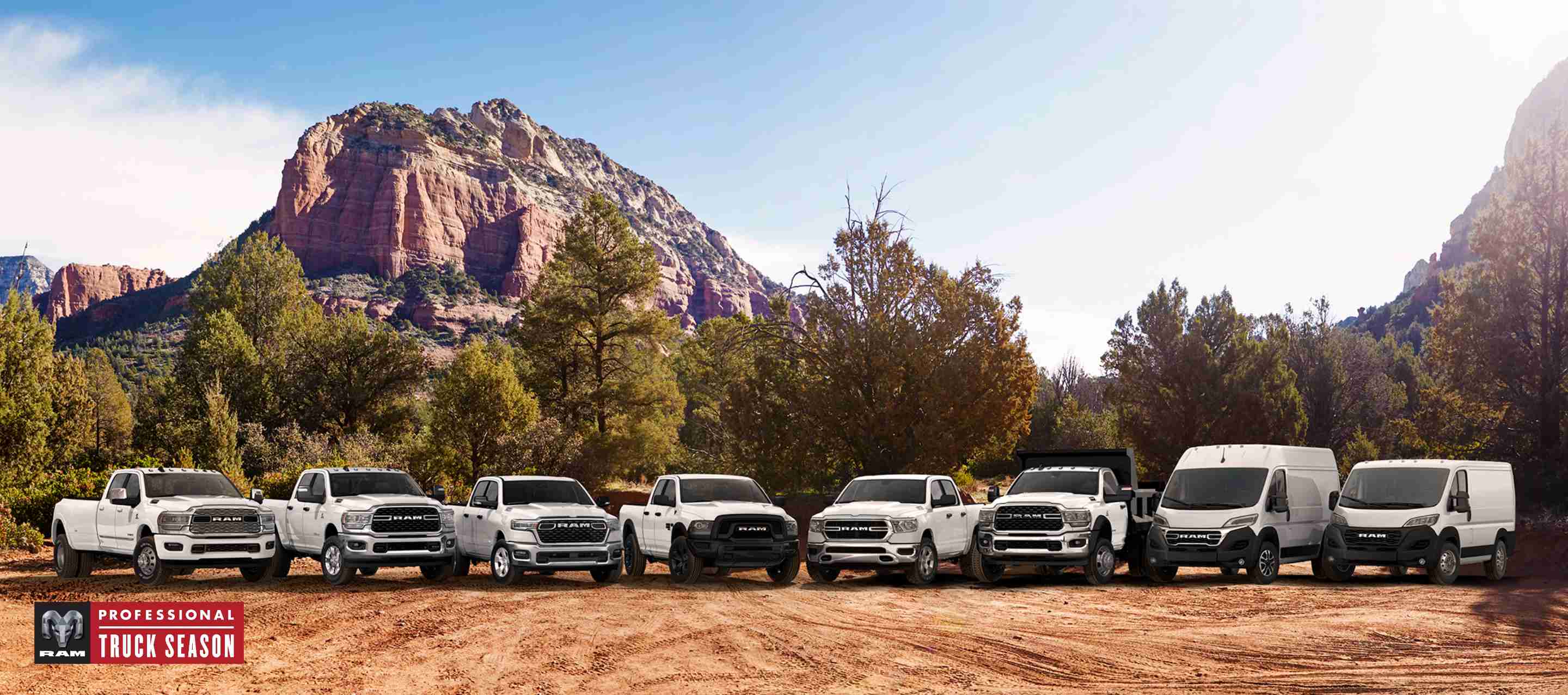 The Ram Brand lineup, all in white, parked side-by-side on a clearing, with mountains in the background. From left to right: a 2024 Ram 3500 Limited Crew Cab, a 2024 Ram 2500 Big Horn Crew Cab, a 2025 Ram 1500 Big Horn Crew Cab, a 2024 Ram 1500 Classic Warlock Quad Cab, a 2024 Ram 1500 Tradesman Crew Cab, a Ram 5500 Tradesman Chassis Cab Regular Cab with dump body upfit, a 2024 Ram ProMaster 1500 SLT+ High Roof Cargo Van and a 2024 Ram ProMaster 1500 Tradesman Standard Roof Cargo Van. Professional Truck Season.