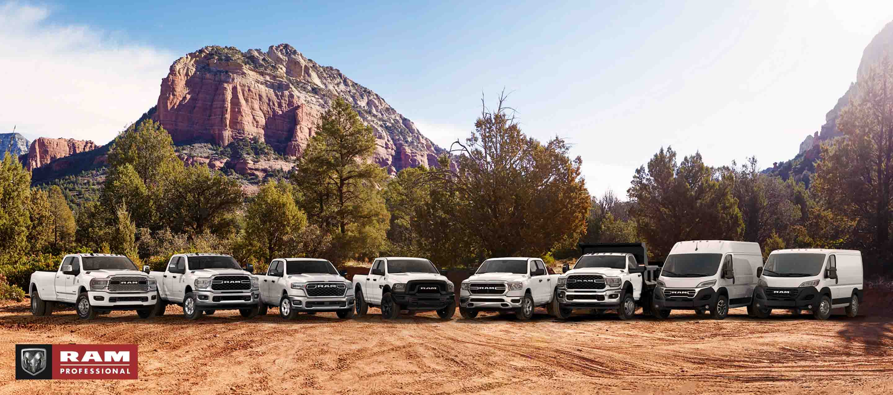 The Ram Brand lineup, all in white, parked side-by-side on a clearing, with mountains in the background. From left to right: a 2024 Ram 3500 Limited Crew Cab, a 2024 Ram 2500 Big Horn Crew Cab, a 2025 Ram 1500 Big Horn Crew Cab, a 2024 Ram 1500 Classic Warlock Quad Cab, a 2024 Ram 1500 Tradesman Crew Cab, a Ram 5500 Tradesman Chassis Cab Regular Cab with dump body upfit, a 2024 Ram ProMaster 1500 SLT+ High Roof Cargo Van and a 2024 Ram ProMaster 1500 Tradesman Standard Roof Cargo Van. Ram Professional.